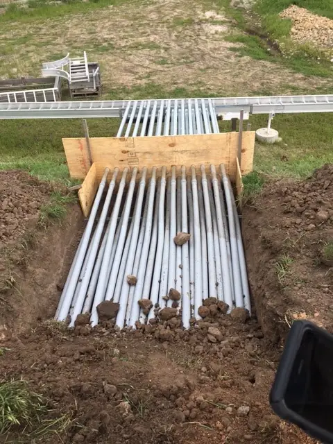 A long conduit run laid in an open trench on a Payne County job